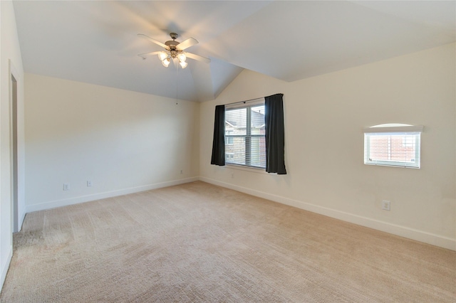 empty room featuring vaulted ceiling, light colored carpet, and ceiling fan