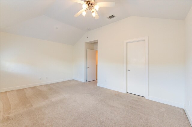 unfurnished bedroom with ceiling fan, vaulted ceiling, and light carpet