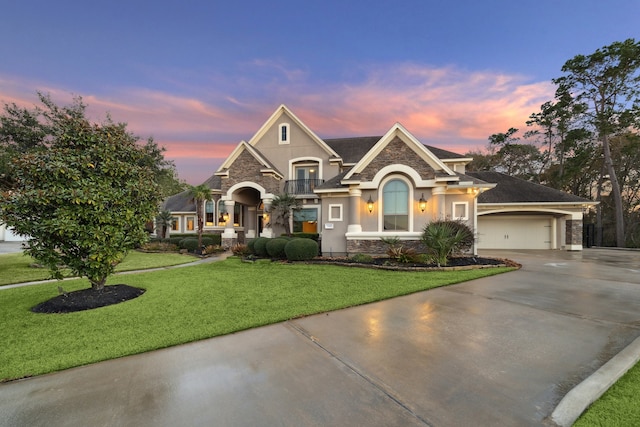 view of front facade with a balcony, a garage, driveway, stucco siding, and a front yard