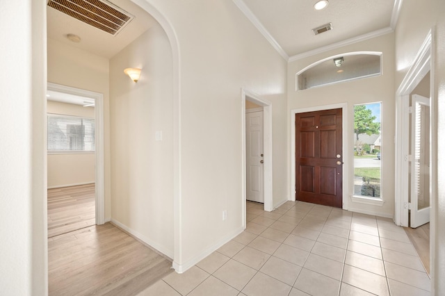 foyer entrance with a high ceiling, ornamental molding, and light tile patterned floors