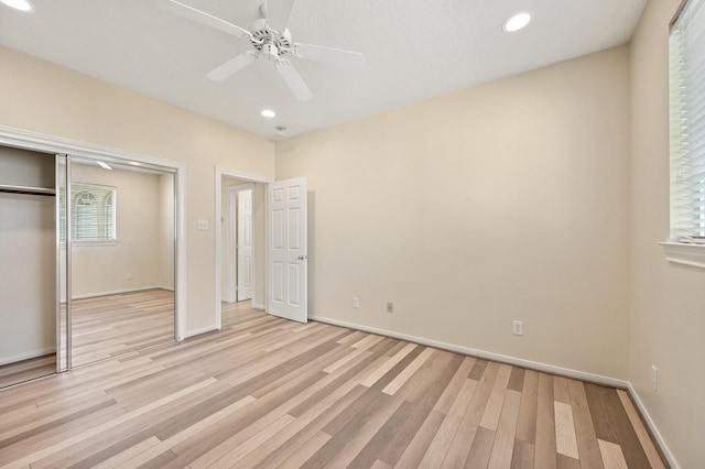 unfurnished bedroom featuring ceiling fan, light hardwood / wood-style floors, and a closet