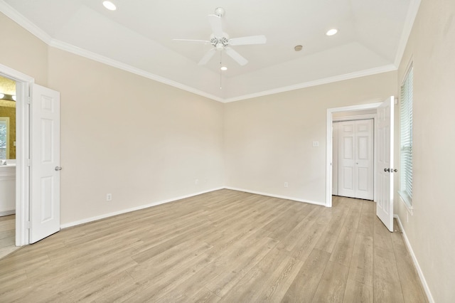 unfurnished room featuring a raised ceiling, ornamental molding, ceiling fan, and light wood-type flooring