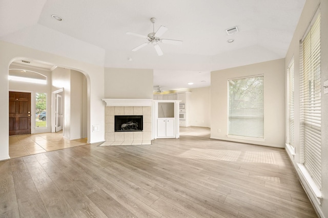 unfurnished living room featuring ceiling fan, light hardwood / wood-style flooring, a fireplace, and a tray ceiling