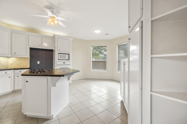 kitchen with a center island, a breakfast bar area, white cabinets, and white appliances