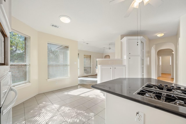 kitchen featuring ceiling fan, light tile patterned floors, stainless steel gas cooktop, and white cabinets