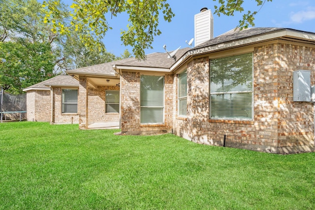 rear view of house featuring a yard and a trampoline