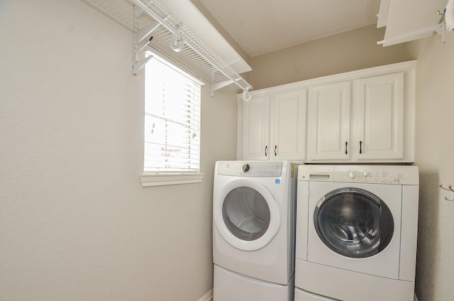 clothes washing area with cabinets and washer and dryer