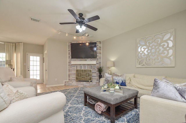 living room featuring a brick fireplace, hardwood / wood-style floors, and ceiling fan