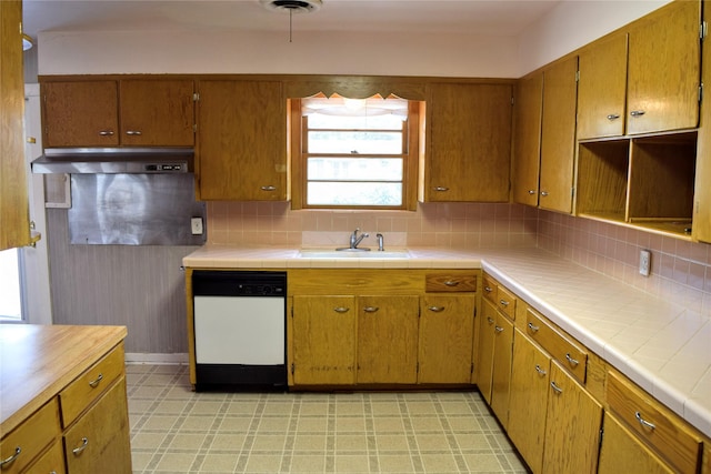 kitchen with tile countertops, dishwasher, sink, and decorative backsplash