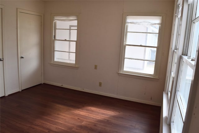 spare room with dark hardwood / wood-style flooring and plenty of natural light
