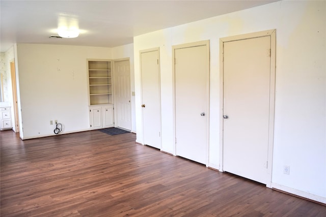 unfurnished bedroom featuring dark wood-type flooring and two closets