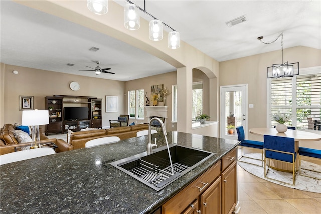 kitchen with sink, decorative light fixtures, dark stone counters, and light tile patterned floors