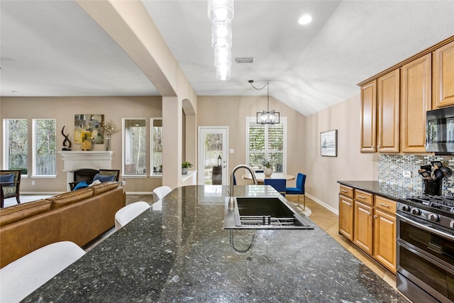 kitchen featuring backsplash, double oven range, hanging light fixtures, and dark stone counters