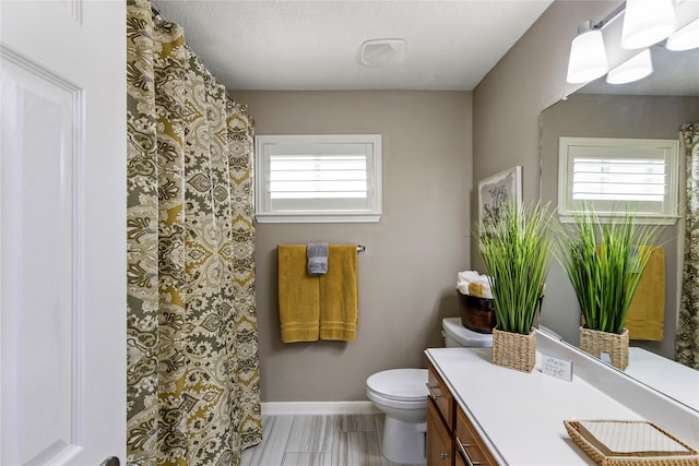 bathroom featuring hardwood / wood-style flooring, vanity, a healthy amount of sunlight, and toilet