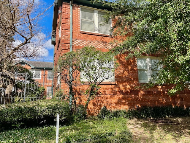 view of home's exterior featuring fence and brick siding