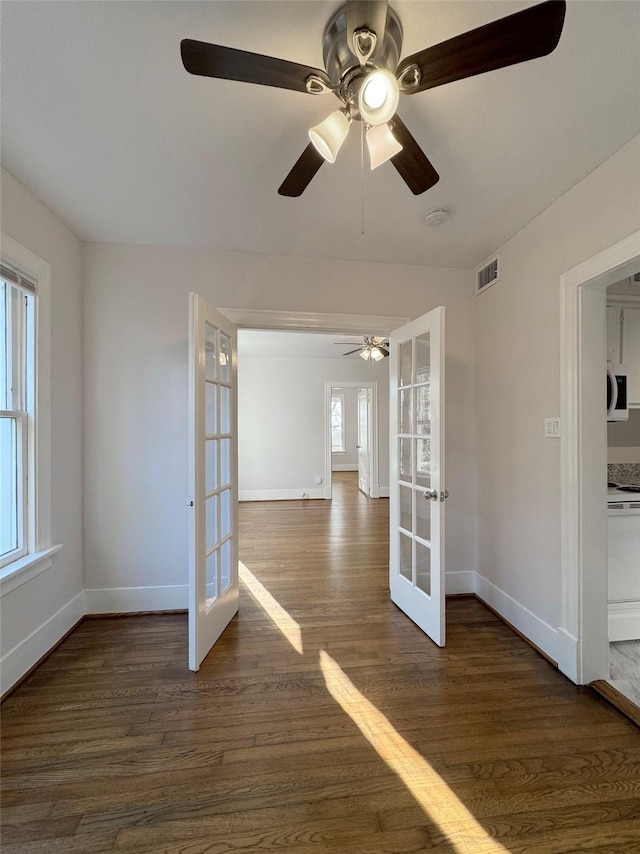 spare room featuring dark wood-type flooring, french doors, visible vents, and baseboards