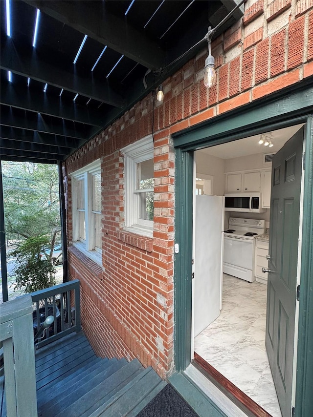 property entrance featuring brick siding and visible vents