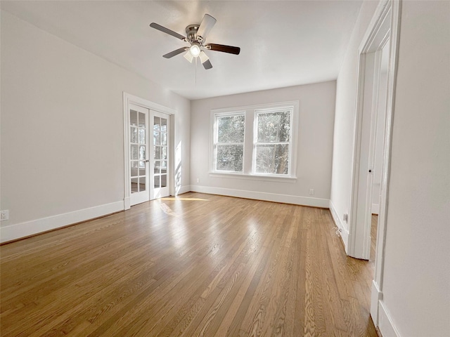 empty room featuring a ceiling fan, baseboards, wood finished floors, and french doors