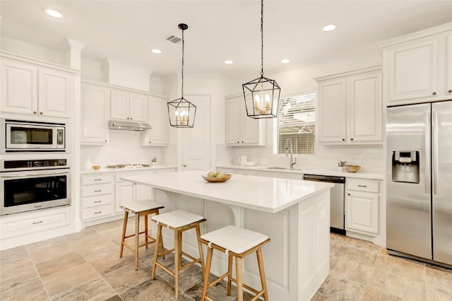 kitchen with sink, a center island, built in appliances, white cabinets, and a kitchen bar