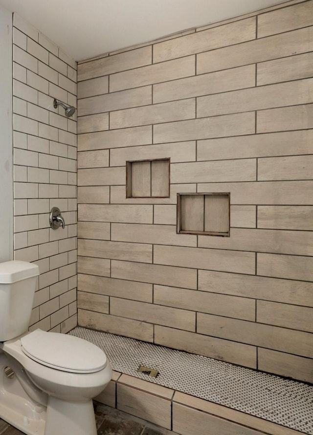 bathroom featuring toilet and a tile shower