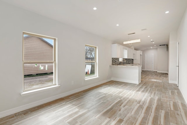 unfurnished living room featuring lofted ceiling and light hardwood / wood-style floors