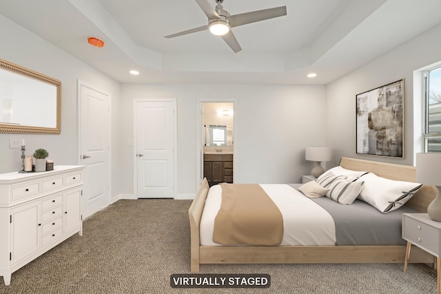 carpeted bedroom with a tray ceiling and ensuite bath