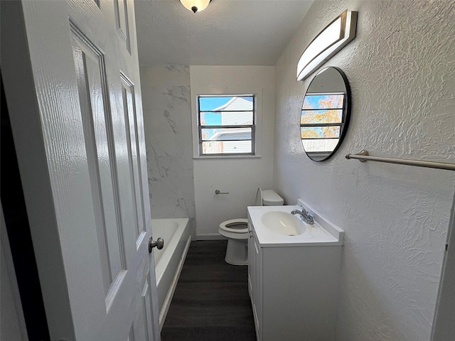 bathroom with hardwood / wood-style flooring, vanity, toilet, and a textured ceiling