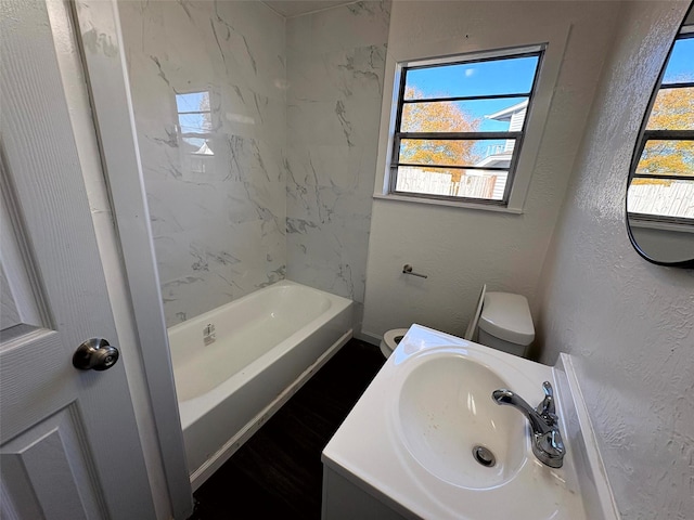 full bathroom featuring vanity, hardwood / wood-style flooring, tiled shower / bath combo, and toilet