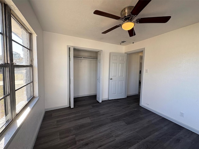 unfurnished bedroom with dark hardwood / wood-style floors, a textured ceiling, ceiling fan, and a closet