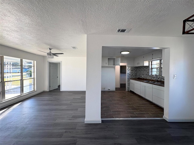 kitchen with sink, ceiling fan, white cabinets, dark hardwood / wood-style flooring, and decorative backsplash