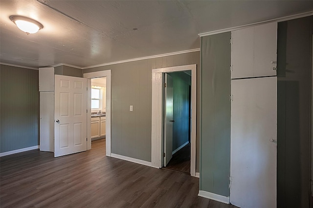 unfurnished bedroom featuring dark wood-type flooring, a closet, ornamental molding, and baseboards