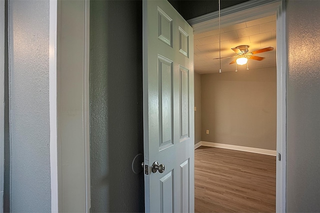 corridor featuring attic access, baseboards, and wood finished floors