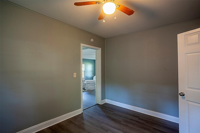 spare room with a ceiling fan, dark wood finished floors, and baseboards