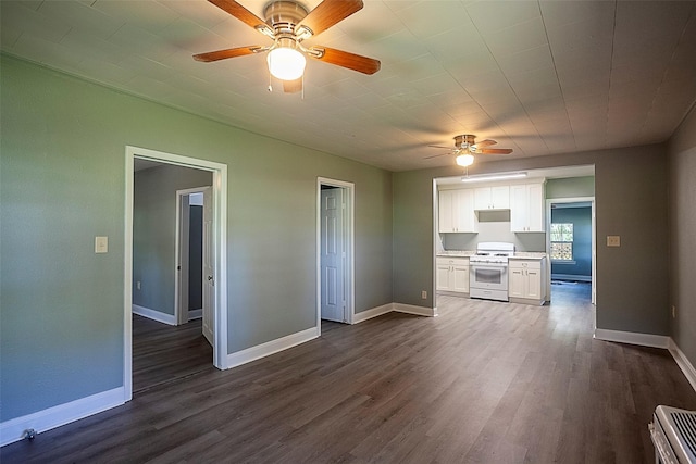 kitchen featuring dark wood-type flooring, white gas stove, white cabinets, and ceiling fan