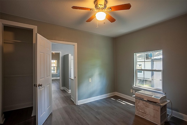 unfurnished bedroom featuring dark wood-style flooring, a ceiling fan, and baseboards