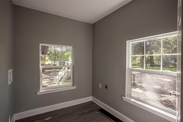 empty room featuring lofted ceiling, dark wood-style flooring, and baseboards