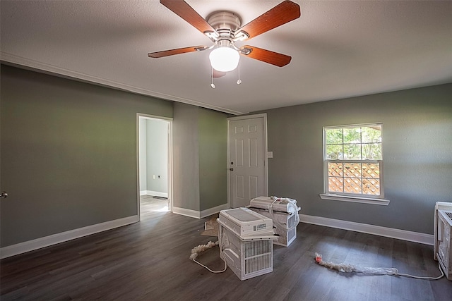 interior space featuring dark wood-type flooring, a ceiling fan, and baseboards