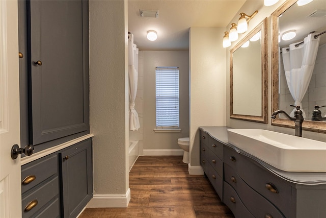 full bathroom featuring wood-type flooring, toilet, shower / bath combo with shower curtain, and vanity