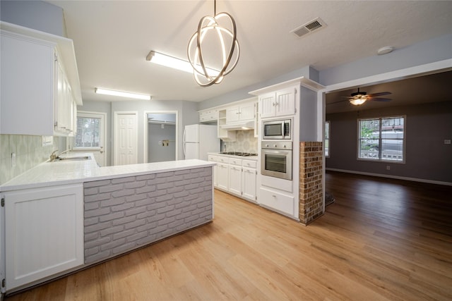 kitchen with pendant lighting, stainless steel appliances, kitchen peninsula, and white cabinets