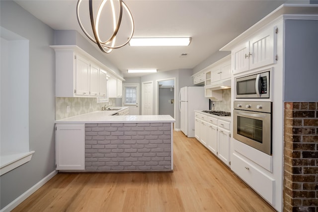 kitchen with tasteful backsplash, white cabinets, kitchen peninsula, stainless steel appliances, and light wood-type flooring