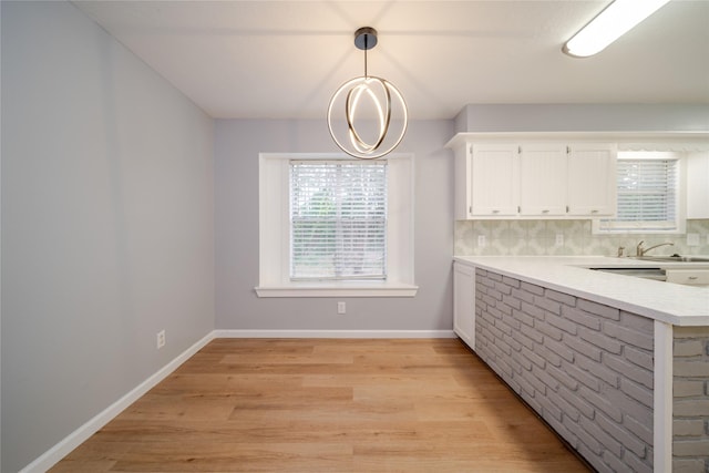 kitchen with sink, pendant lighting, light hardwood / wood-style floors, decorative backsplash, and white cabinets