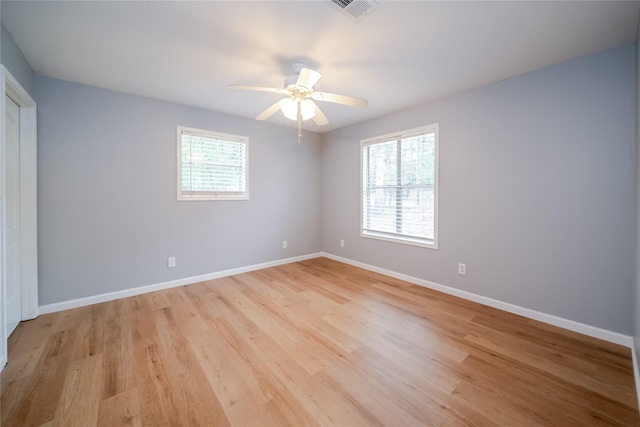 spare room featuring a wealth of natural light, ceiling fan, and light hardwood / wood-style flooring