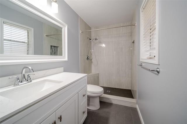 bathroom with vanity, toilet, and a tile shower