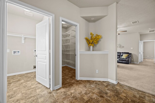 hall featuring carpet and a textured ceiling