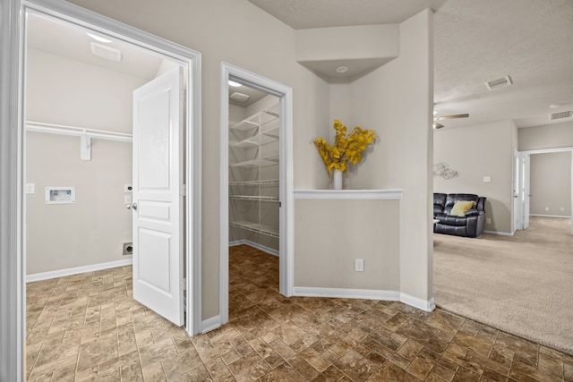 corridor with stone finish floor, carpet floors, visible vents, and baseboards