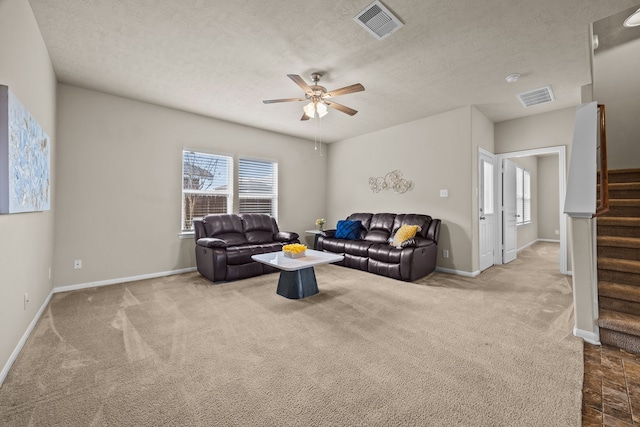 carpeted living room featuring ceiling fan, a wealth of natural light, and a textured ceiling