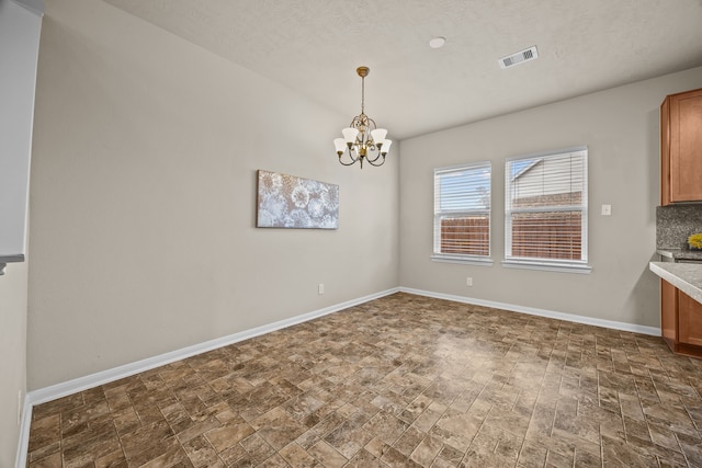 unfurnished dining area featuring a chandelier, visible vents, and baseboards