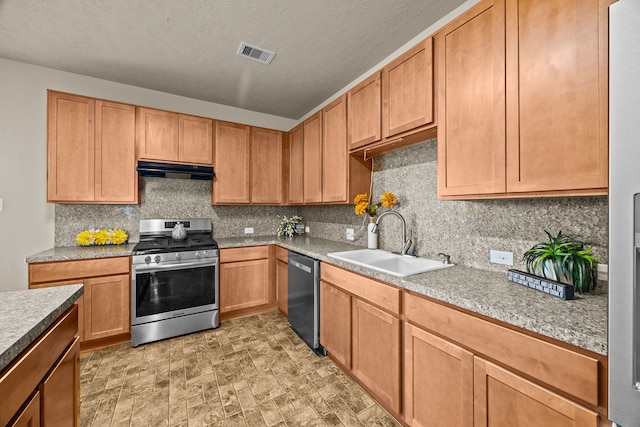 kitchen with appliances with stainless steel finishes, sink, backsplash, and a textured ceiling