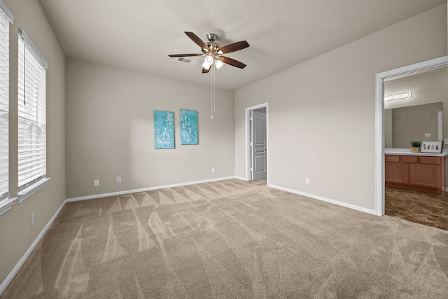 unfurnished bedroom featuring light carpet, ensuite bath, and ceiling fan