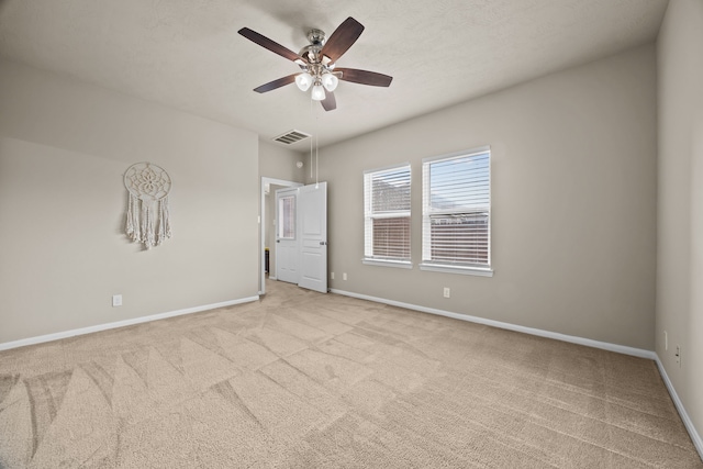 empty room featuring ceiling fan, carpet, visible vents, and baseboards